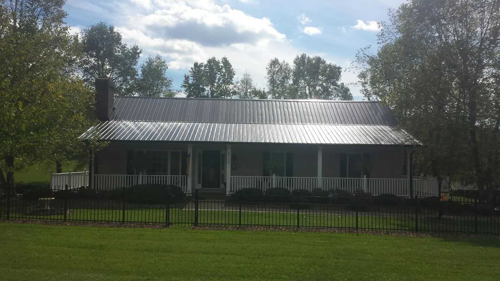 Gray metal roof on a brick ranch with a full width front porch — Gutter Guard Installation work by our crew in Garden City